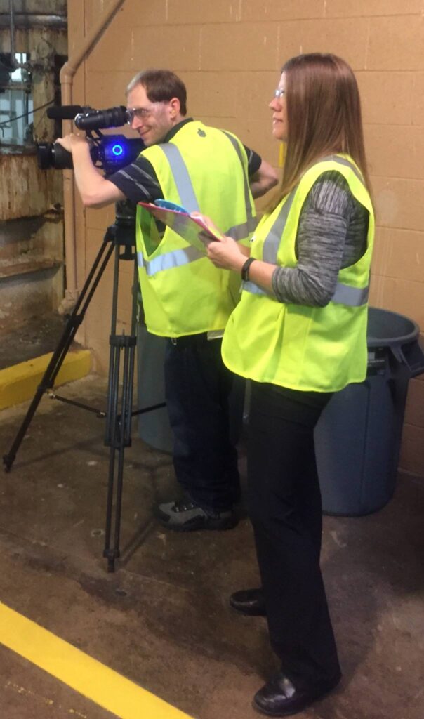 Video production crew filming industrial worker on location in Pennsylvania