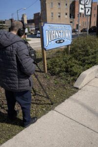 Videographer filming the “Welcome to the City of Johnstown” sign in downtown Johnstown, Pennsylvania.